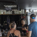 Sales clerk ringing up two customers at restaurant