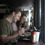 Young man and woman eating at restaurant table