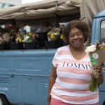 Woman holding bouquet and posing in front of truck full of bouquets