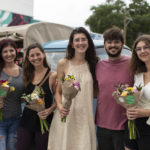 Group of young shoppers posing with bouquets in front bouquet truck