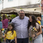 Father and daughters holding bouquets and posing in front of bouquet truck