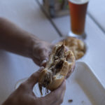 Hands holding a pulled pork sandwich