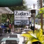 Outdoor patio with dining tables and sign that states "Zudar's"