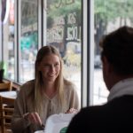 Young woman eating food with friend at restaurant