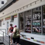 Two customers walking into Zudar's restaurant