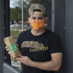Man in mask posing for camera with his food order