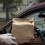 Brown paper bag with food being handed to customer in car