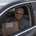 Man posing with to-go food order in car