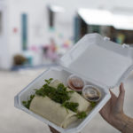 Person holding to-go food container with two burritos inside