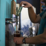 Bartender dispensing tap beer into glass cup