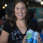 Woman posing for camera and holding 4-pack of beer
