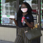 Woman holding pizza box and posing for camera