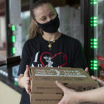 Young woman receiving two boxes of pizza