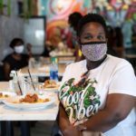 Woman in mask sitting at restaurant table posing for camera