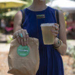 Woman holding a drink and brown bag