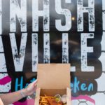 Chicken tenders and french fries in to-go food container with sign that states "Nashville"