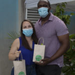 Man and woman smiling for camera and holding giftbag