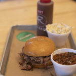 Tray with pulled pork sandwich, baked beans and coleslaw on tray