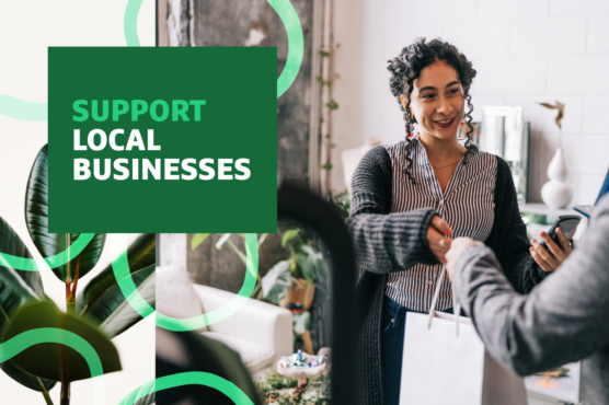 Woman with dark curly hair taking possession of the bag containing her purchase with the headline "Support Local Businesses" overlaid.