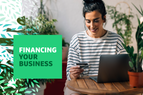 "Financing Your Business" text over image of a woman sitting at a laptop holding a credit card