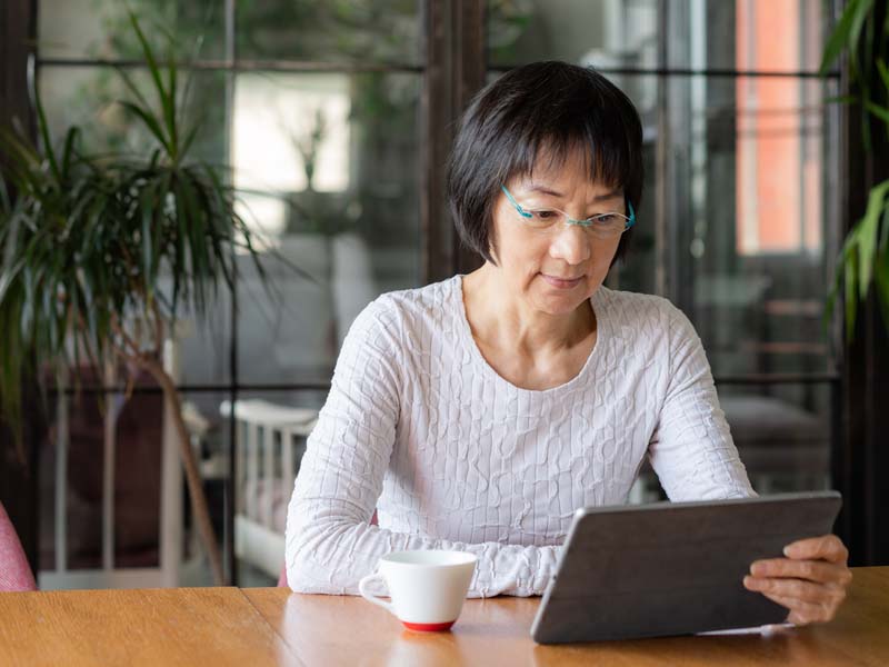 Woman sitting at table looking at tablet