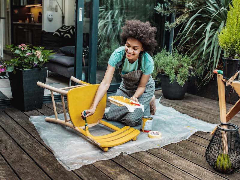 Woman painting wooden chair outside