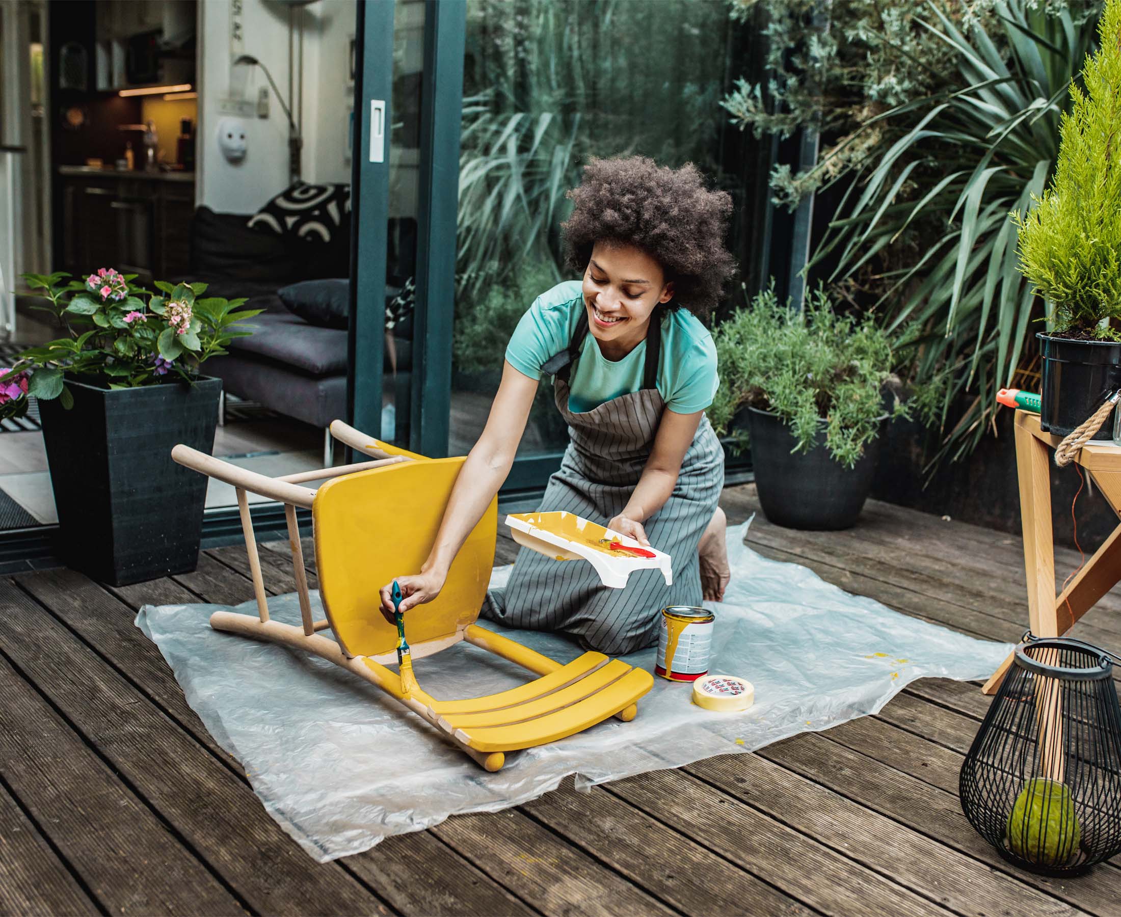 Woman painting wooden chair outside