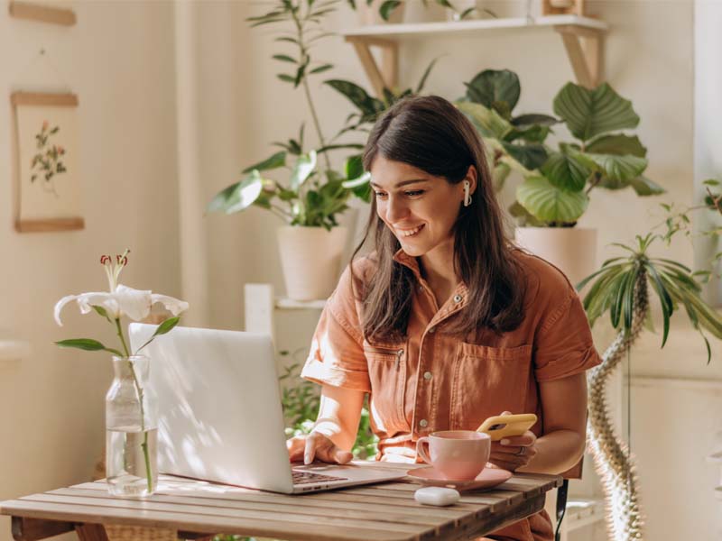 Woman sitting at table with coffee and laptop