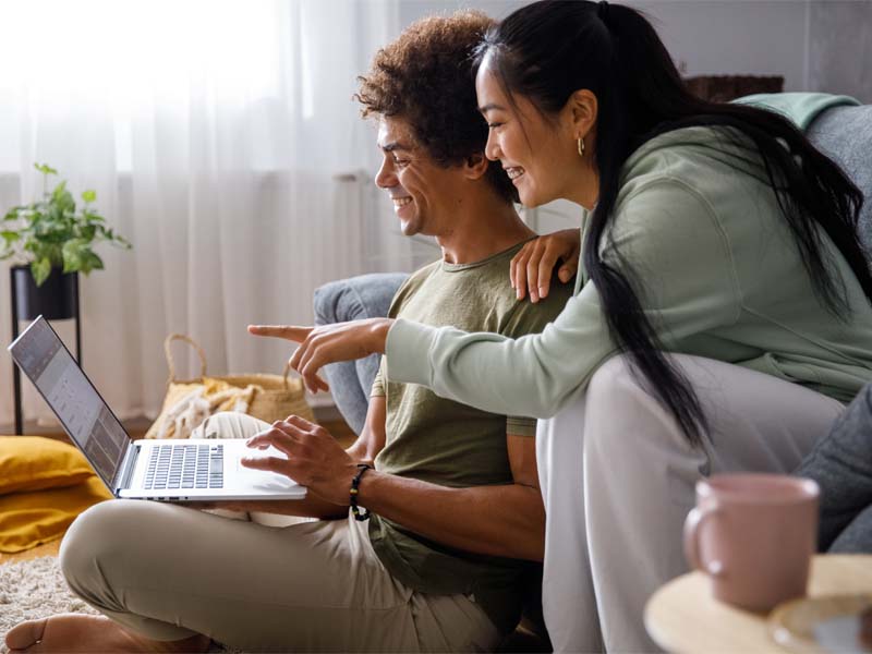 Male and female looking at laptop in living room