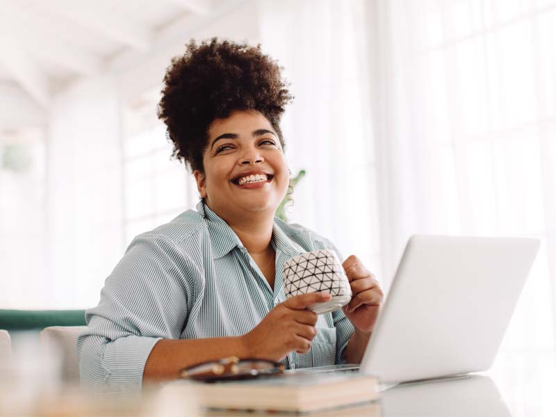 Woman sitting at table with coffee and laptop