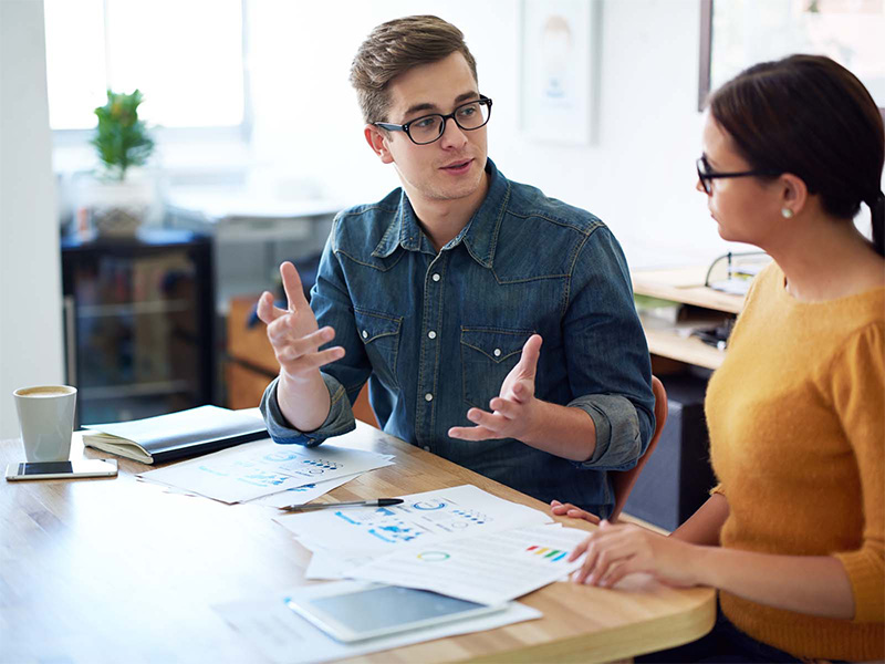 Male and female talking at desk