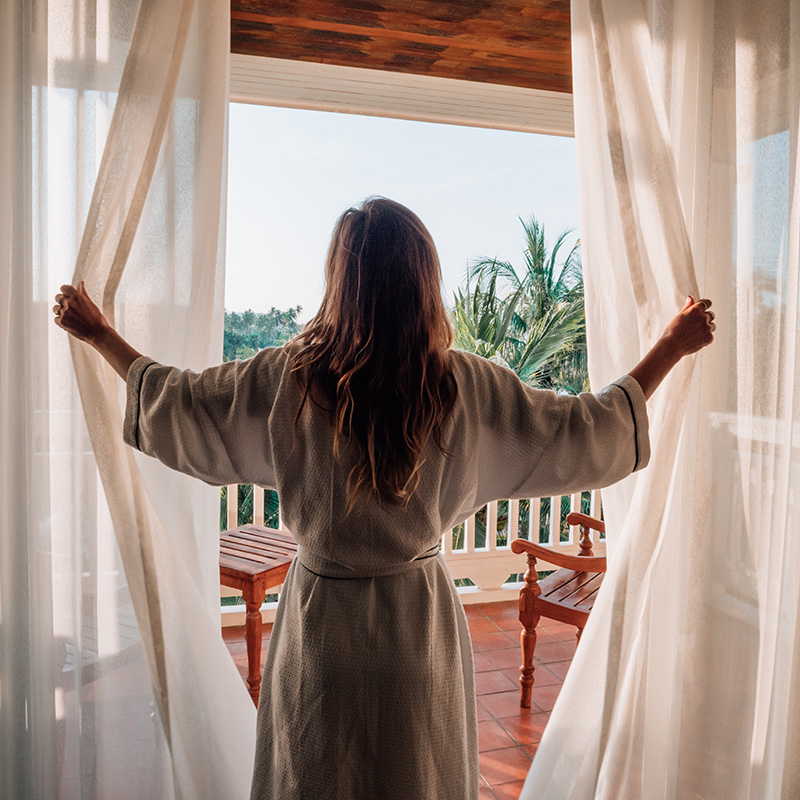 Woman opening drapes in a hotel room