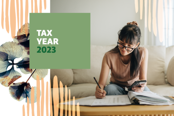 Woman sitting on couch with calculator and pen working on financial paperwork on coffee table with headline tax year 2023.