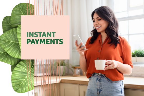Person smiling and looking at a smartphone next to a graphic with the text "Instant Payments" in a modern kitchen setting.