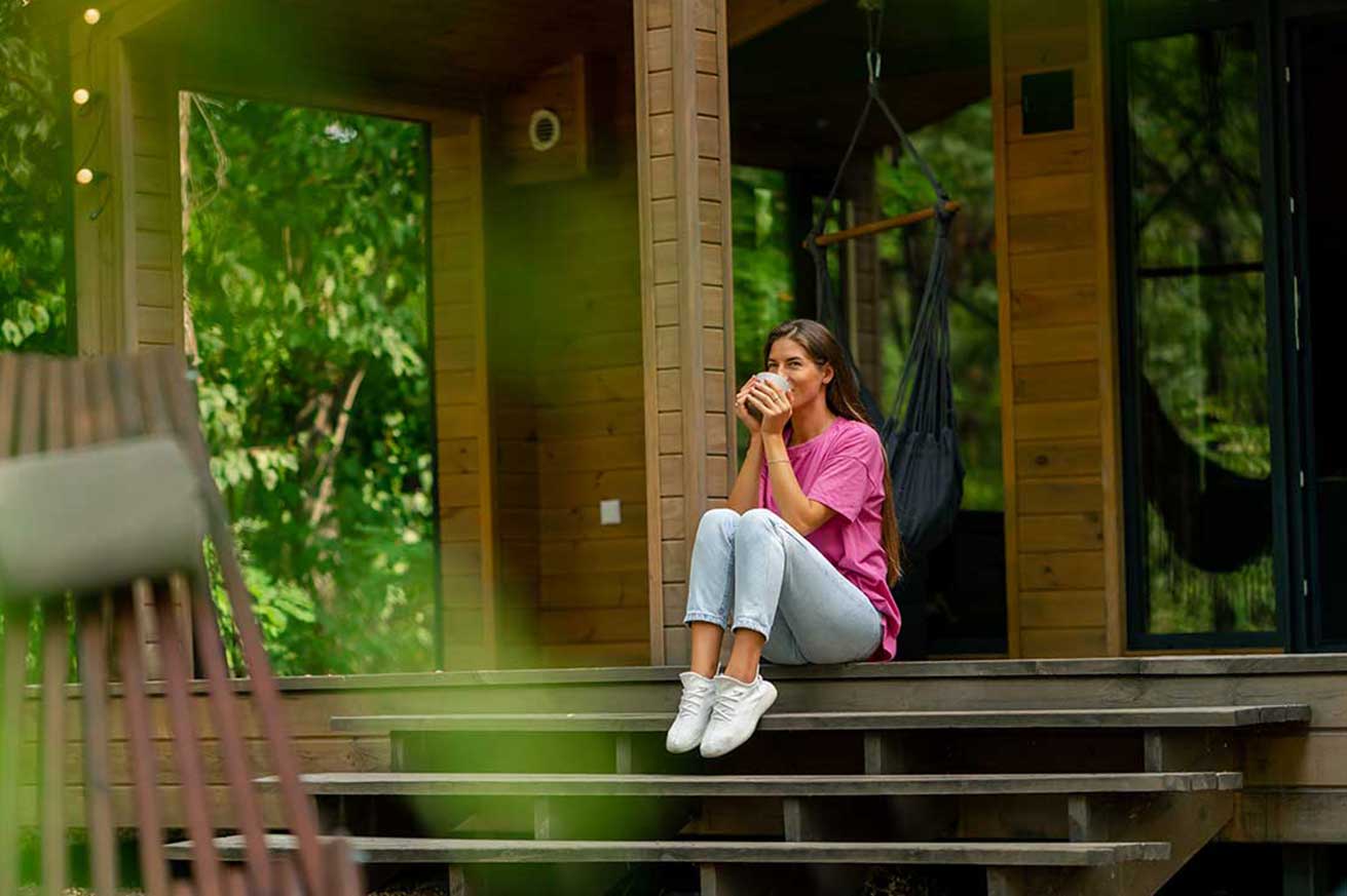 Woman drinking coffee on the front porch of a house