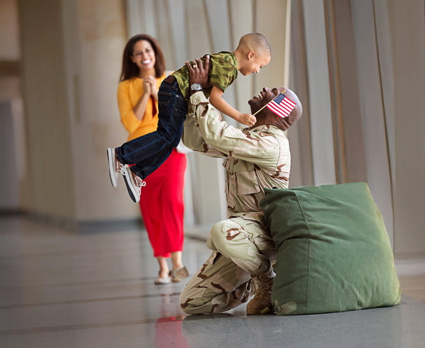 Man in military uniform holding his child in the air and smiling