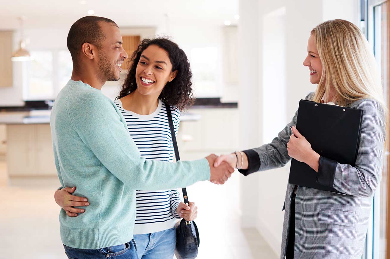 Two people stand together looking at a two‑story house with a front porch, with an Equal Housing Lender logo shown in the corner.