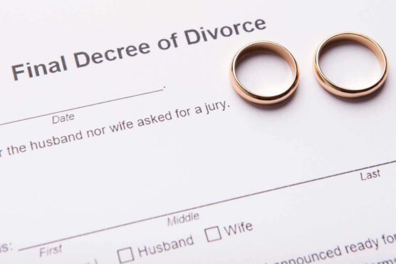 Two gold wedding rings rest on top of a legal document titled “Final Decree of Divorce.”